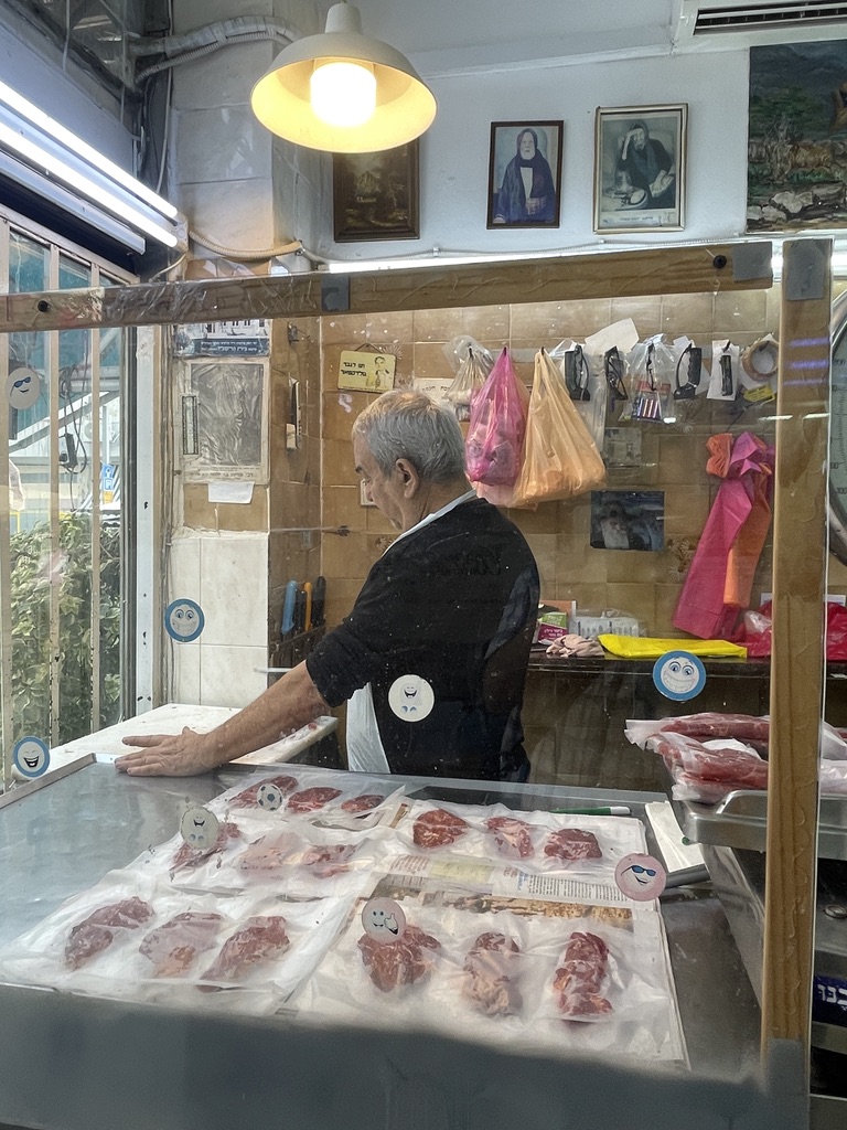 Menachem Okunis behind the counter at Atliz Mercaz Levinsky butcher shop in Levinsky Market, continuing a Salonikan Jewish butchery tradition in Tel Aviv
