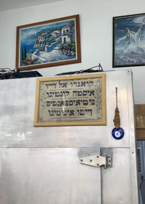 Ladino proverb displayed inside Atliz Mercaz Levinsky butcher shop in Levinsky Market, reflecting Salonikan Jewish language and tradition in Tel Aviv